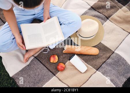 Nahaufnahme Frau sitzt auf karierten mit Buch über Picknick im Park Stockfoto