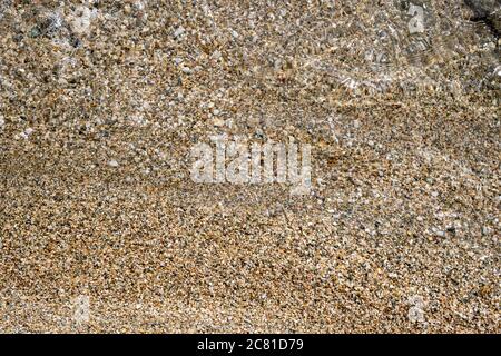 Kleine Kieselsteine und Sand Meeresboden Hintergrund Textur unter klarem Kristall seichtes Meerwasser, Draufsicht. Stockfoto