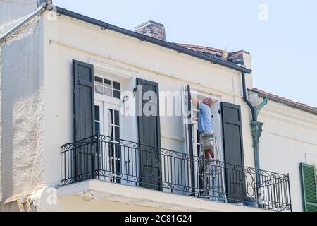 New Orleans, Louisiana/USA - 17. Juli 2020: Mann, der Fensterrahmen vor dem historischen Gebäude im French Quarter putzt Stockfoto