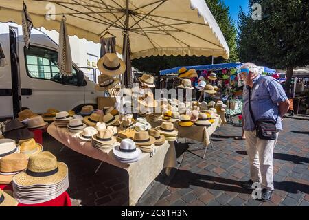 Mann, der Strohhüte im französischen Freiluftmarkt betrachtet - Loches, Indre-et-Loire, Frankreich. Stockfoto