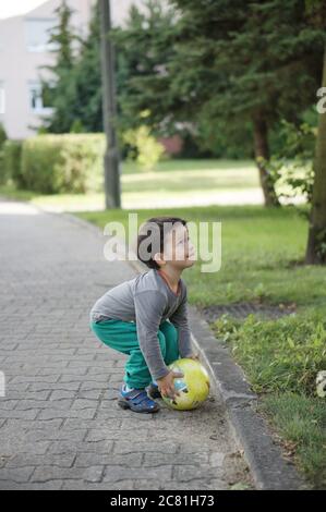 POSEN, POLEN - 13. Jul 2017: Drei Jahre altes Kind spielt mit einem Ball auf einer Straße in der Stadt Stockfoto