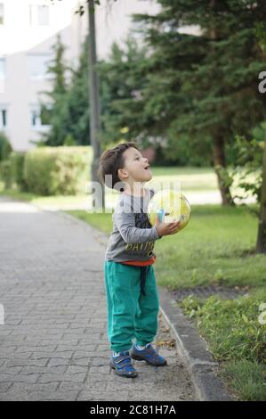 POSEN, POLEN - 13. Jul 2017: Drei Jahre altes Kind spielt mit einem Ball auf einer Straße in der Stadt Stockfoto