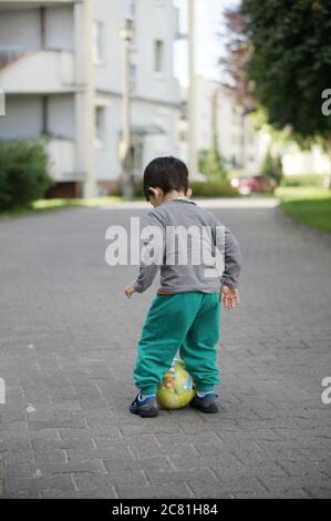 POSEN, POLEN - 13. Jul 2017: Drei Jahre altes Kind spielt mit einem Ball auf einer Straße in der Stadt Stockfoto