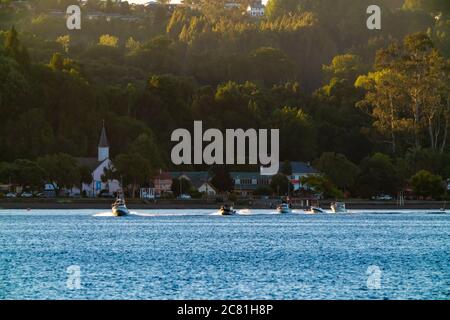 Beeindruckende Aussicht auf den See Llanquihue mit Motorbooten, die bei Sonnenuntergang segeln. Frutilllar, Lake District Stockfoto