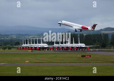 Glasgow, Schottland, Großbritannien. Juli 2020. Im Bild: Loganair Embraer ERJ145 Flugzeug gesehen am Flughafen Glasgow mit einer großen Gruppe von geerdeten British Airways (BA) airbus-Flugzeugen im Hintergrund. Loganair hatte einige Zeitnischen von Flybe nach dem Zusammenbruch von Flybe übernommen, dann traf die Coronavirus-Sperre im März, und seitdem hat Loganair die Dienste erhöht, aber dies sind turbulente Zeiten für alle Fluggesellschaften und die globale Luftfahrtindustrie. Quelle: Colin Fisher/Alamy Live News Stockfoto