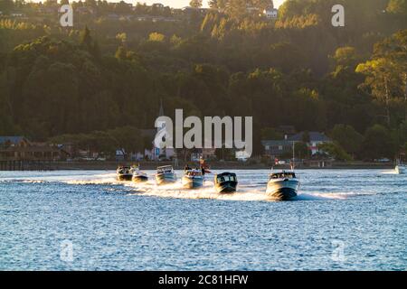 Beeindruckende Aussicht auf den See Llanquihue mit Motorbooten, die bei Sonnenuntergang segeln. Frutilllar, Lake District Stockfoto