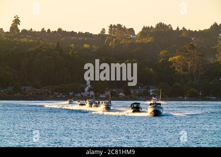 Beeindruckende Aussicht auf den See Llanquihue mit Motorbooten, die bei Sonnenuntergang segeln. Frutilllar, Lake District Stockfoto