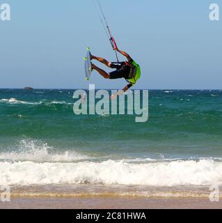 Kitesurfer oder Kiteboarder, die seitlich hängen Kitesurfen am Strand von Somo an einem sonnigen, windigen Nachmittag Santander Cantabria Spanien Sommer Stockfoto