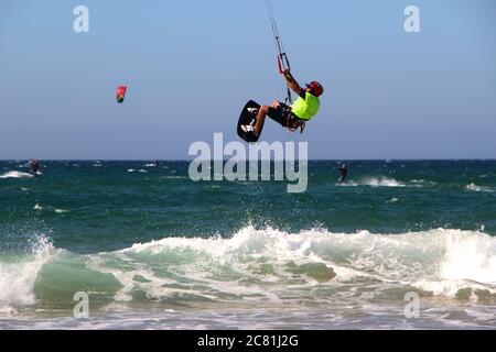 Kitesurfer oder Kiteboarder springen Kitesurfen vom Strand von Somo an einem sonnigen, windigen Nachmittag Santander Cantabria Spanien Sommer Stockfoto