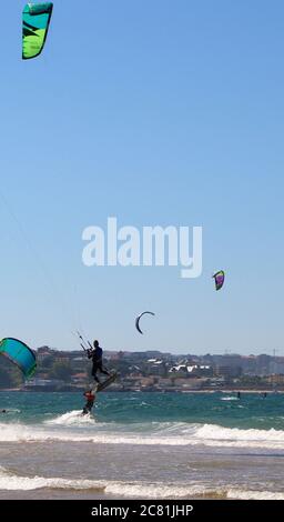 Kitesurfer oder Kiteboarder springen Kitesurfen vom Strand von Somo an einem sonnigen, windigen Nachmittag Santander Cantabria Spanien Sommer Stockfoto