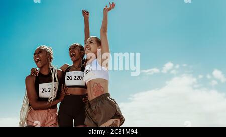 Junge Mannschaft von weiblichen Athleten genießen Sieg. Eine vielfältige Gruppe von Läufern feiert Erfolg. Stockfoto
