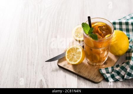 Eistee-Drink mit Zitrone im Glas und Eis auf weißem Holztisch Stockfoto
