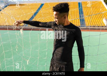 Junge gutaussehende afroamerikanische Sportler im Fußballtor im Stadion stehen Stockfoto