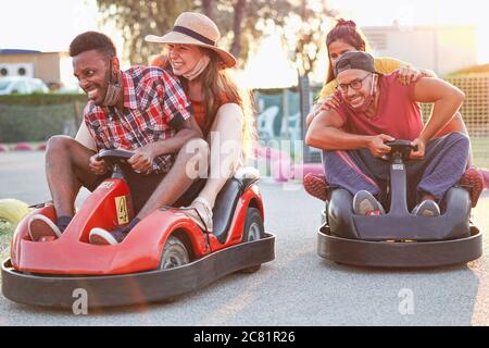 Gruppe von multitnischen Freunden Spaß mit Go Kart - Junge Menschen mit Gesichtsmaske auf lächelnd und fröhlich bei Mini-Autorennen - Paare draußen in doub Stockfoto