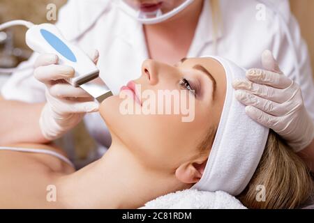 Kosmetologie und Beauty-Konzept - schöne Frau erhalten Ultraschall Kavitation Gesichtspeeling Verfahren Stockfoto