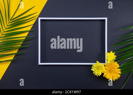 Rahmen aus tropischen Palmenblättern und Blumen auf schwarzem und gelbem Hintergrund. Flach liegend, Draufsicht, Kopierbereich. Sommer Hintergrund, Natur. Kreative Rahmenkonstruktion Stockfoto