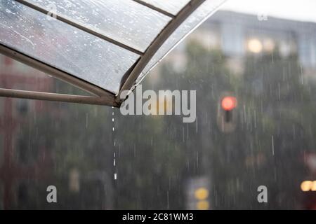 Heftiger Regen tropft vom Dach, während ein Rot Ampel leuchtet Stockfoto