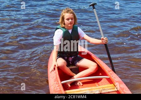 Aktiver glücklicher Junge im Sommerurlaub. Teenager Schuljunge Spaß genießen abenteuerliche Erfahrung Kajakfahren auf See an einem sonnigen Tag im Sommer Stockfoto