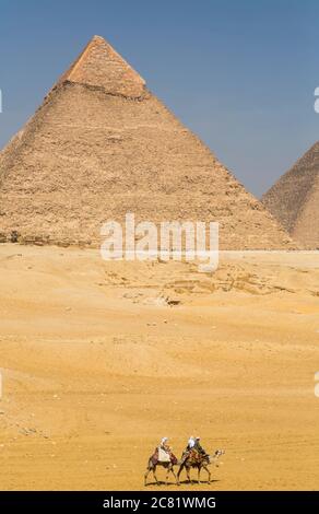 Touristen reiten Kamele, Pyramide von Khepre, Giza Pyramid Complex, UNESCO-Weltkulturerbe; Giza, Ägypten Stockfoto