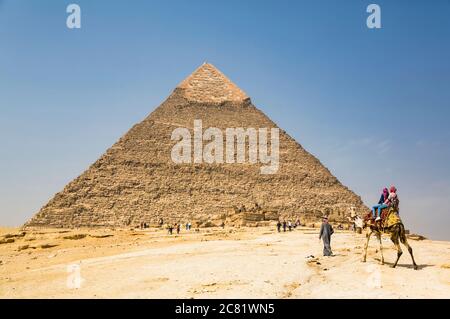 Touristen reiten ein Kamel, Pyramide von Khafre, Giza Pyramid Complex, UNESCO-Weltkulturerbe; Giza, Ägypten Stockfoto
