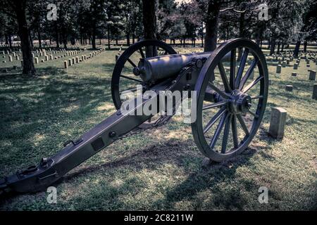 Ein Kanonenrelikt aus dem amerikanischen Bürgerkrieg überblickt den Stones River National Cemetery voller internierter Union Soldaten in Murfreesboro, TN, USA Stockfoto