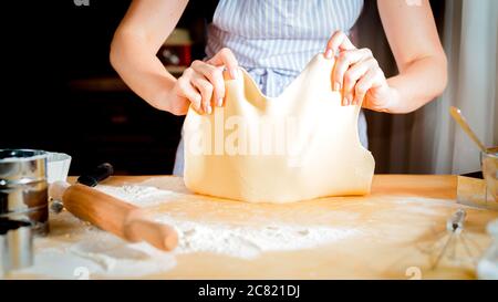 Teig mit weiblichen Händen auf Holztisch machen Stockfoto