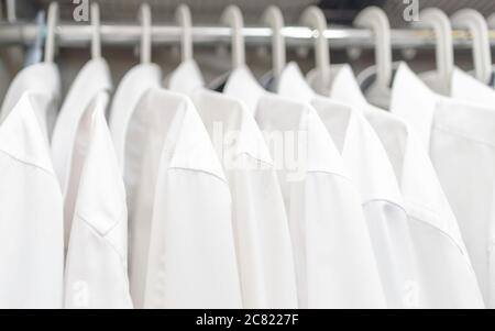 Weiße Herrenhemden hängen an den Schultern im Schrank Stockfoto