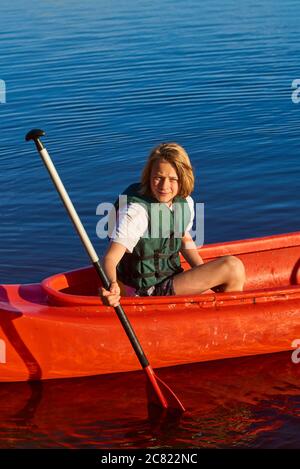 Aktiver glücklicher Junge im Sommerurlaub. Teenager Schuljunge Spaß genießen abenteuerliche Erfahrung Kajakfahren auf See an einem sonnigen Tag im Sommer Stockfoto