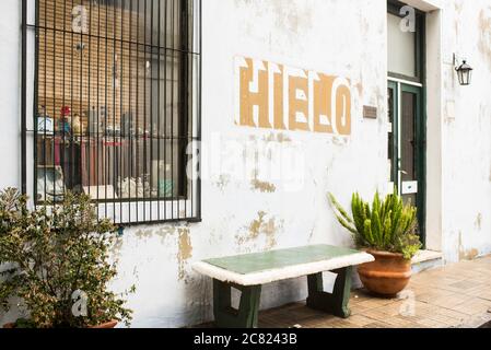 Colonia del Sacramento / Uruguay; 2. Januar 2019: Historisches Viertel der Touristenstadt, Bank und Mauer mit dem Text Eis Stockfoto