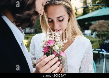Nahaufnahme romantischen Bräutigam und wunderschöne Braut sinnlich halten Blumenstrauß im Freien Stockfoto