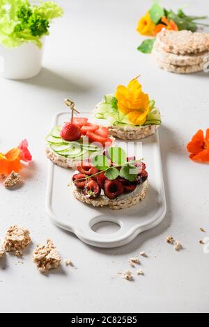 Reis Knäckebrot mit Belag von Friuts und Gemüse auf weiß. Vegane Snacks. Nahaufnahme. Vertikal. Stockfoto