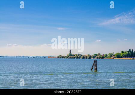 Panoramablick auf die Insel Mazzorbo im Wasser der Lagune von Venedig mit dem Glockenturm der Kirche Chiesa di Santa Caterina und dem Sumpf. Blick von der Insel Burano. Provinz Venedig, Region Venetien, Norditalien Stockfoto