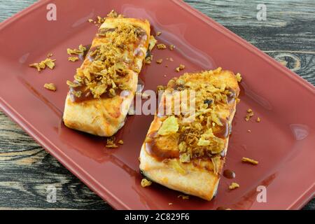 Gebackene Lachsfischfilets mit Grillsauce und knusprigen Zwiebelüberschlägen auf der Esstablette auf dem Tisch Stockfoto