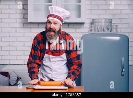 Ein Koch in einer Schürze macht einen Salat aus Gemüse und Pizza. Stockfoto