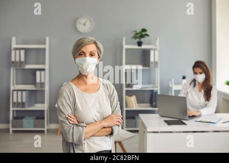 Frau Senior in Schutzmaske Besuch in der Klinik Büro. Stockfoto