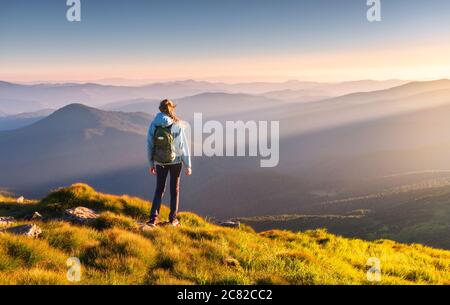 Schöne Berge im Nebel und stehende junge Frau mit Rucksack Stockfoto