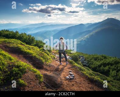 Berge und stehende junge Frau mit Rucksack auf dem Trail Stockfoto