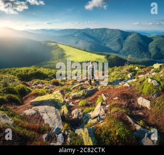 Berge und stehende junge Frau mit Rucksack auf den Steinen Stockfoto