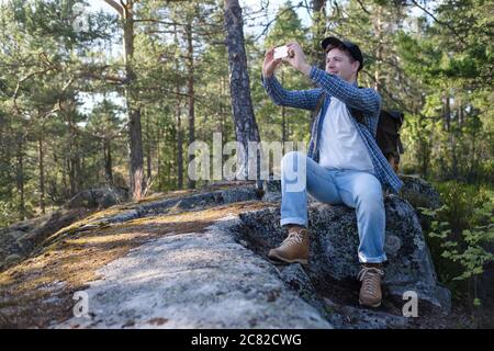 Junger Kaukasischer, der mit seinem Smartphone während einer Wanderung durch den Wald fotografiert Stockfoto