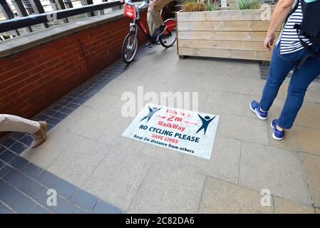 London, England, Großbritannien. COVID-19 Vorsichtsmaßnahmen auf der Südbank. Schilder, die soziale Distanzierung und kein Radfahren - Radfahrer ignorieren die Schilder Stockfoto