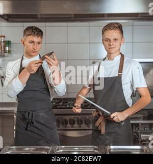 Junger Koch schärft Messer in der Küche Stockfoto