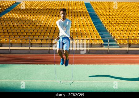 Junger, hübscher afroamerikanischer Sportler, der beim Training im Stadion auf Springseil springt Stockfoto