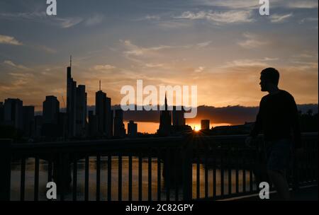 20. Juli 2020, Hessen, Frankfurt/Main: Ein Mann geht über die Floßbrücke, während die Sonne hinter den Wolkenkratzern der Bankenstadt untergeht. Foto: Arne Dedert/dpa Stockfoto