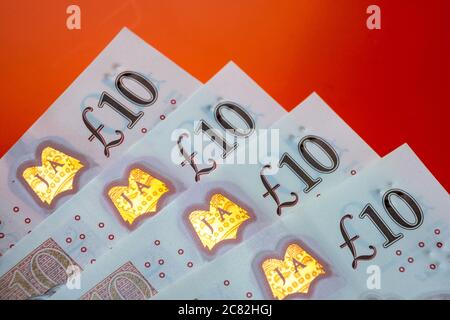 Britische Pfund Sterling Banknoten. Ecken von 10 Pfund Noten platziert eine auf der anderen auf dem lebendigen orage-roten Hintergrund. Stockfoto