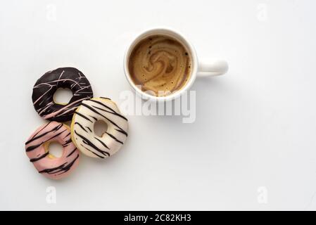 Über dem Kopf Schuss von leckeren Donuts mit einer Tasse Kaffee Auf einer weißen Oberfläche Stockfoto