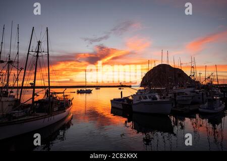 Feuriger Sonnenuntergang spiegelt sich in Morro Bay unter den Fischerbooten an einem ruhigen Abend Stockfoto