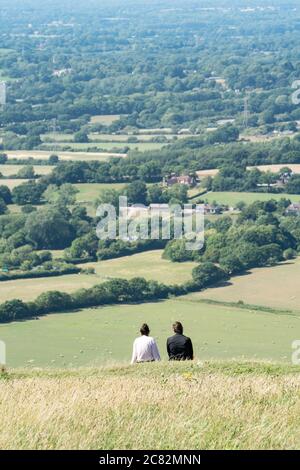 Junges Paar auf einem Hügel, das den Blick über das Devil's Deich Valley, South Downs, Sussex, Großbritannien, bewundert Stockfoto
