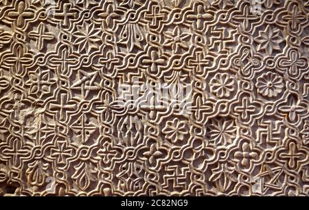 Byzantinisch gemustertes Ornament in Steinwand geschnitzt, alte Textur Hintergrund, Detail der Innenausstattung mit geometrischen Relief. Symbole Muster eingeschrieben Stockfoto