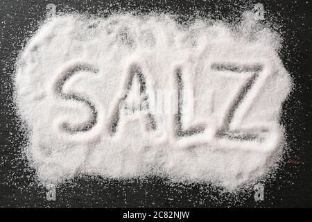 Salz, übersetzt in verschütteten Salzkristallen auf dunklem Schiefer, von oben aus in hoher Winkelansicht, ausgewählter Fokus Stockfoto