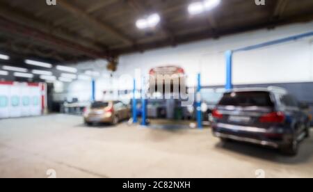 Auto-Reparatur-Werkstatt Innenraum in Bokeh, verschwommen defokussieren Hintergrund. Auto auf Lift in Mechaniker-Werkstatt oder Garage, Fahrzeuge in der Wartung, Arbeitsplatz A Stockfoto